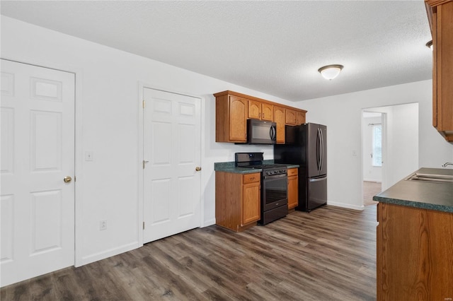 kitchen with a textured ceiling, sink, dark hardwood / wood-style flooring, and black appliances