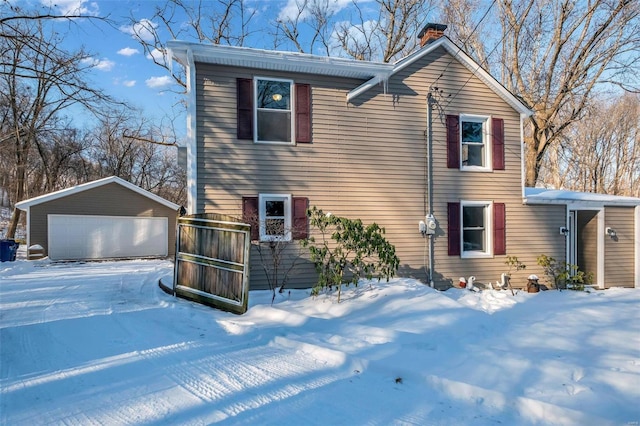 snow covered property with a garage and an outbuilding