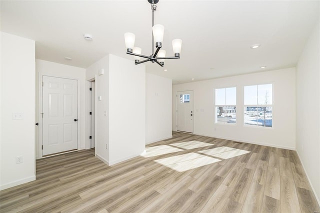 spare room with light wood finished floors, baseboards, a notable chandelier, and recessed lighting