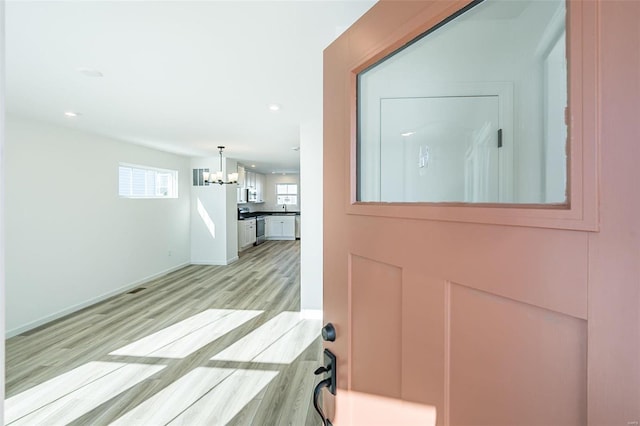 corridor with a chandelier, baseboards, light wood-style flooring, and recessed lighting