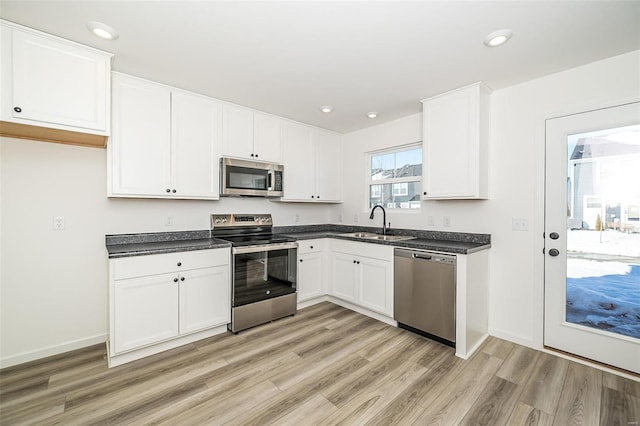 kitchen with dark countertops, white cabinets, stainless steel appliances, and a sink