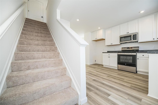 stairway featuring baseboards, wood finished floors, and recessed lighting