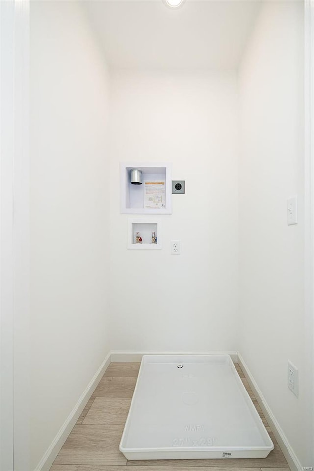 clothes washing area with hookup for a washing machine, hookup for an electric dryer, light wood-type flooring, laundry area, and baseboards