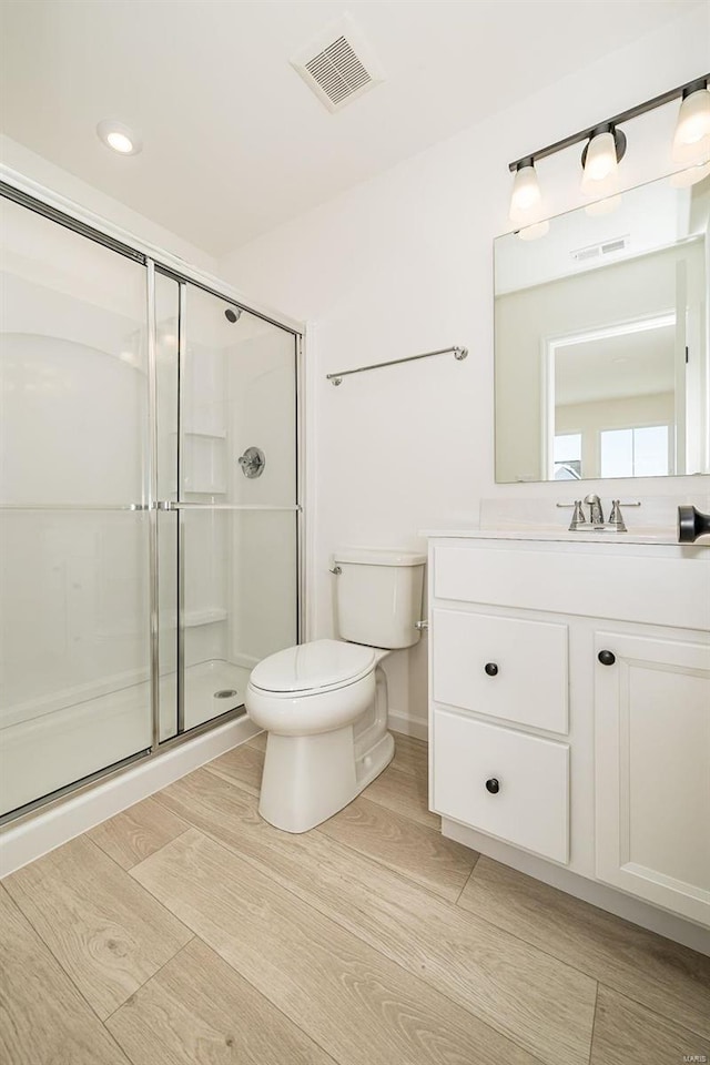 full bath with wood finish floors, visible vents, toilet, a shower stall, and vanity