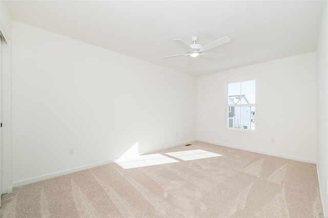 carpeted empty room with a ceiling fan and baseboards