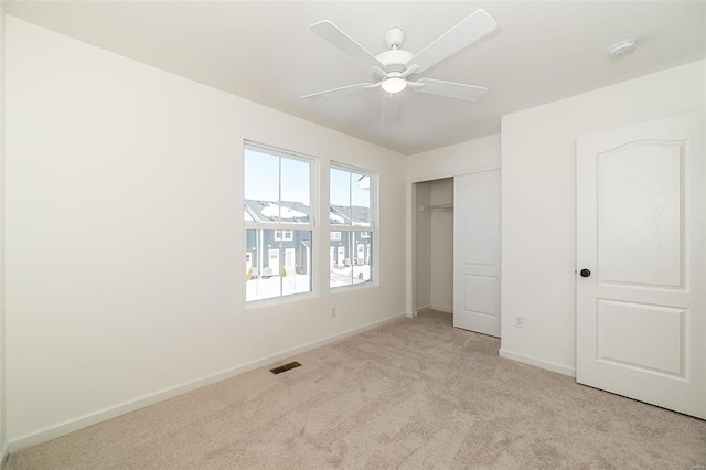 unfurnished bedroom with ceiling fan, light colored carpet, visible vents, baseboards, and a closet