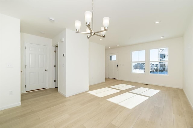 unfurnished room featuring light wood-type flooring and an inviting chandelier