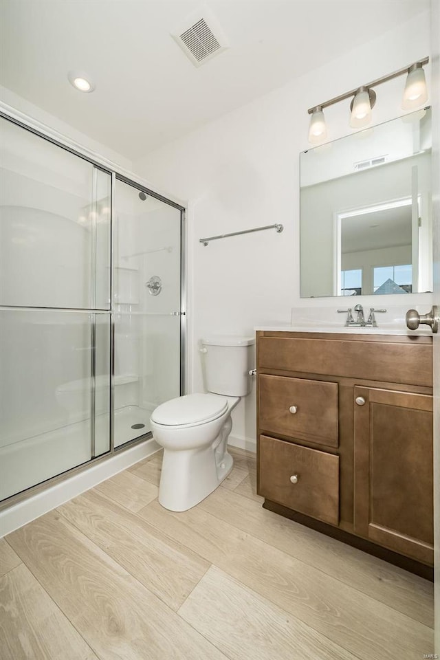 bathroom with vanity, toilet, a shower with door, and hardwood / wood-style flooring