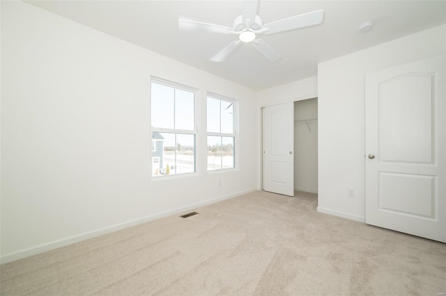 unfurnished bedroom featuring ceiling fan, a closet, and light carpet