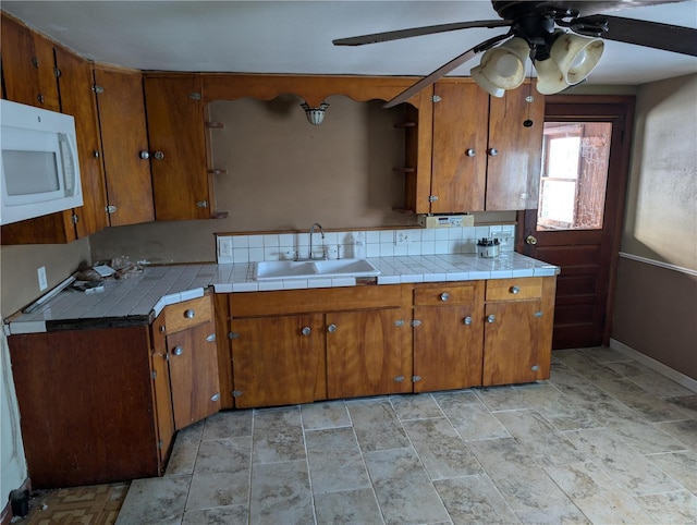 kitchen featuring ceiling fan, sink, and tile counters