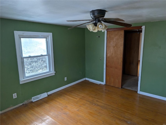 unfurnished bedroom with light wood-type flooring, ceiling fan, and a closet