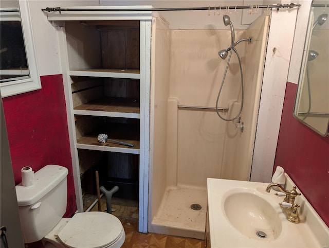 bathroom featuring sink, toilet, a shower, and parquet flooring