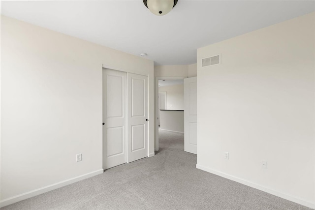 unfurnished bedroom with light carpet and a closet