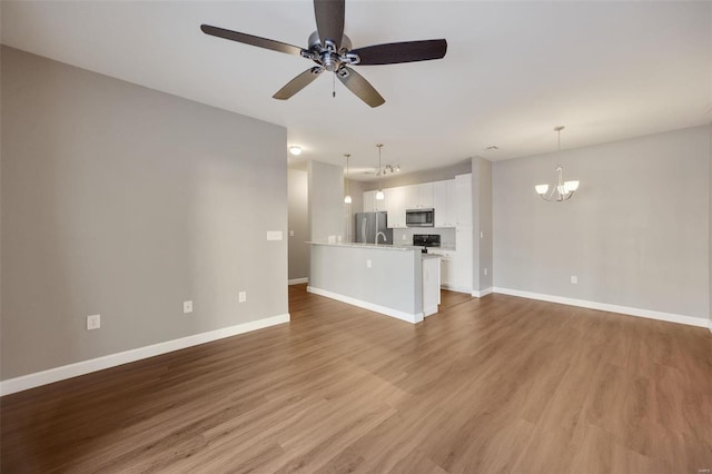 unfurnished living room featuring hardwood / wood-style floors and ceiling fan with notable chandelier