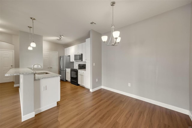 kitchen with light stone countertops, white cabinetry, decorative light fixtures, a kitchen island with sink, and appliances with stainless steel finishes