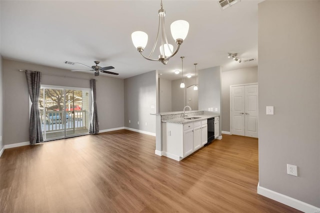 kitchen featuring light stone countertops, white cabinetry, sink, hanging light fixtures, and ceiling fan with notable chandelier