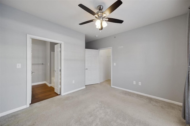 unfurnished bedroom featuring ceiling fan, light colored carpet, a spacious closet, and connected bathroom