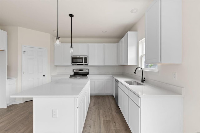 kitchen featuring white cabinets, stainless steel appliances, hanging light fixtures, and sink