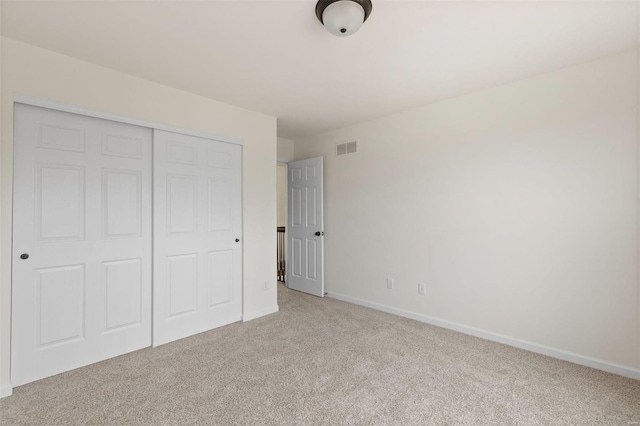 unfurnished bedroom with light carpet and a closet