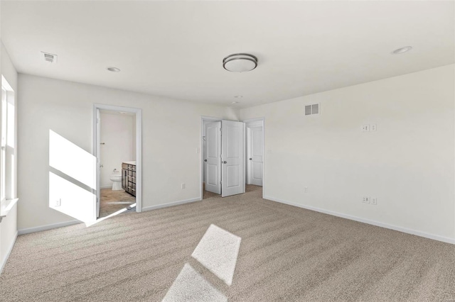 unfurnished bedroom with connected bathroom and light carpet