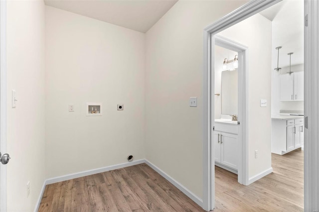 clothes washing area with hookup for an electric dryer, sink, hookup for a washing machine, and light hardwood / wood-style flooring