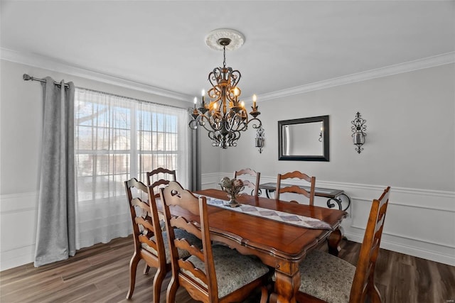 dining area with dark wood-type flooring, ornamental molding, and a chandelier