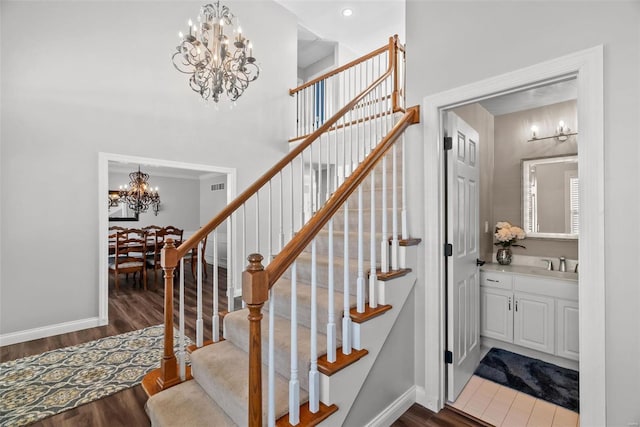 stairway with sink, a notable chandelier, hardwood / wood-style floors, and crown molding