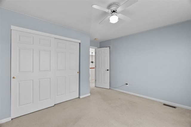 unfurnished bedroom with ceiling fan, light colored carpet, and a closet