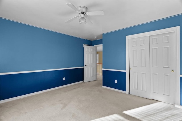 unfurnished bedroom featuring ceiling fan, a closet, and light carpet