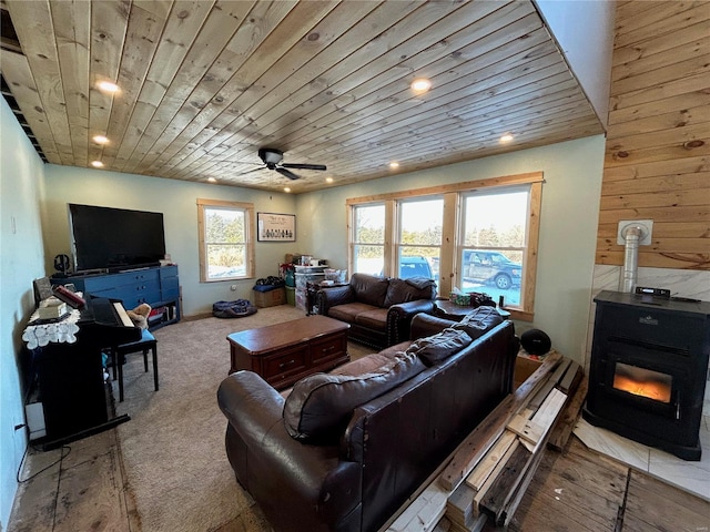 living room with a wood stove, ceiling fan, and wooden ceiling