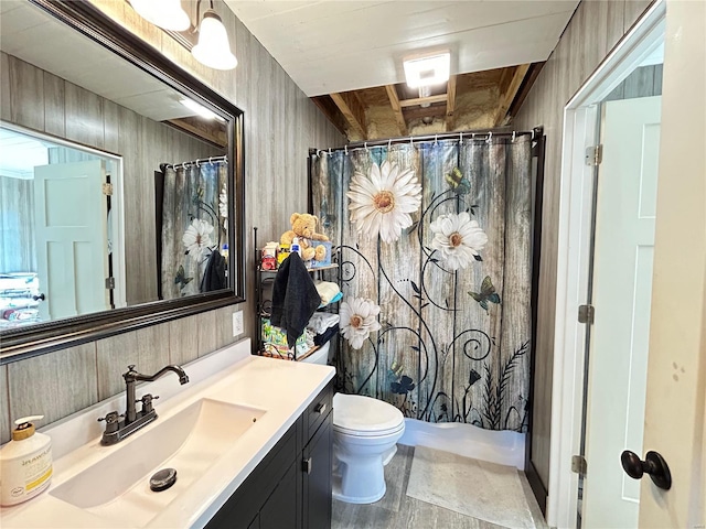 bathroom with a shower with curtain, vanity, toilet, and wooden walls