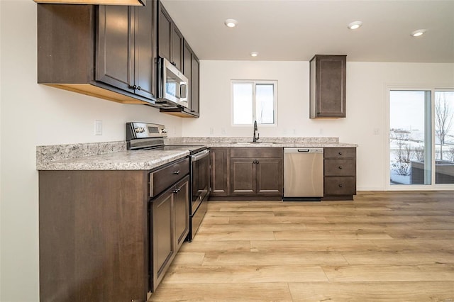 kitchen featuring appliances with stainless steel finishes, sink, light hardwood / wood-style floors, plenty of natural light, and dark brown cabinets