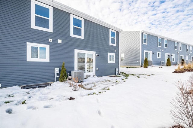 snow covered rear of property featuring cooling unit