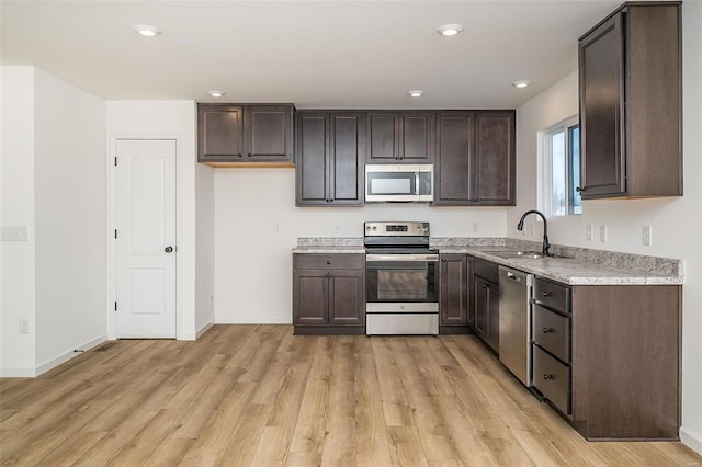 kitchen featuring stainless steel appliances, sink, and light hardwood / wood-style flooring