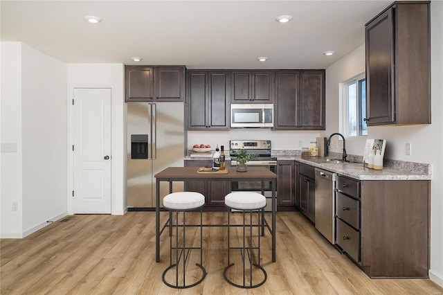 kitchen with sink, a center island, dark brown cabinets, light hardwood / wood-style flooring, and appliances with stainless steel finishes