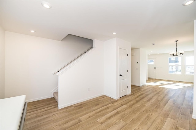 unfurnished living room with a notable chandelier and light hardwood / wood-style flooring