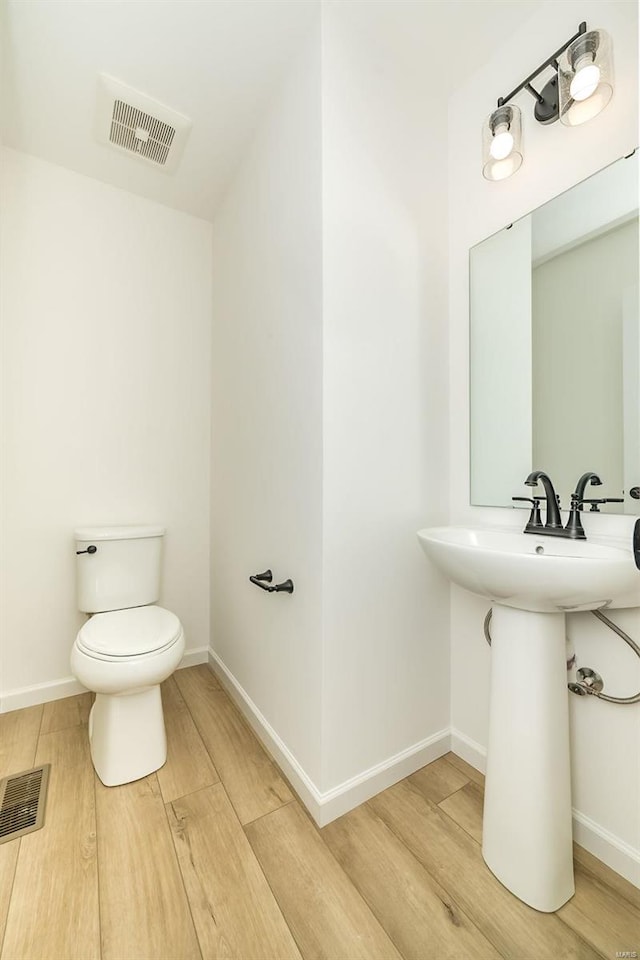 bathroom with toilet, wood-type flooring, and sink