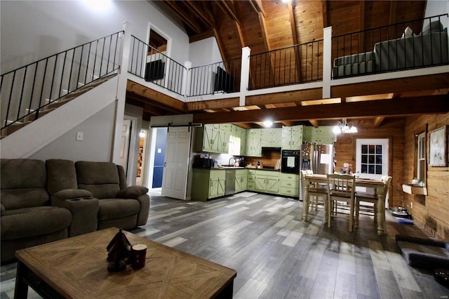 living room with a towering ceiling, hardwood / wood-style floors, wood walls, sink, and a barn door