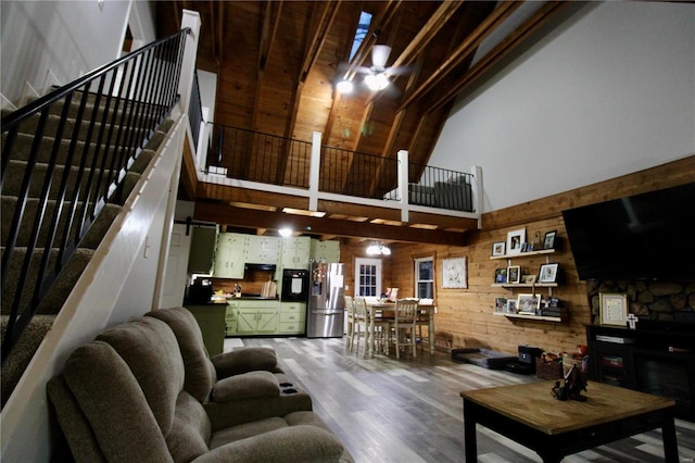 living room with wood-type flooring, wood walls, and a high ceiling