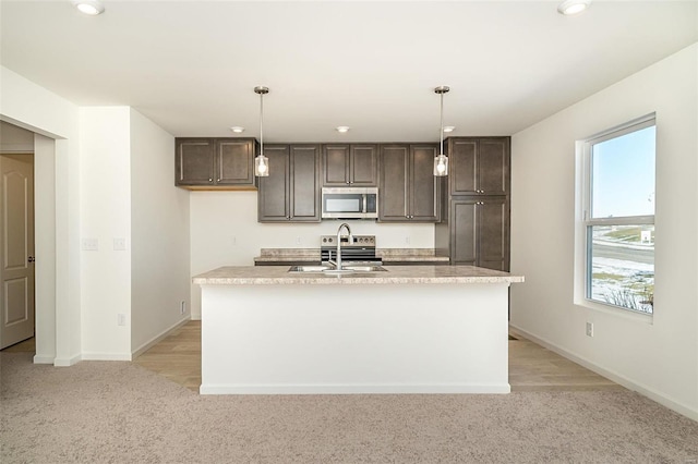 kitchen with pendant lighting, a kitchen island with sink, a healthy amount of sunlight, and appliances with stainless steel finishes