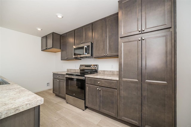 kitchen with stainless steel appliances, dark brown cabinets, and light wood-type flooring