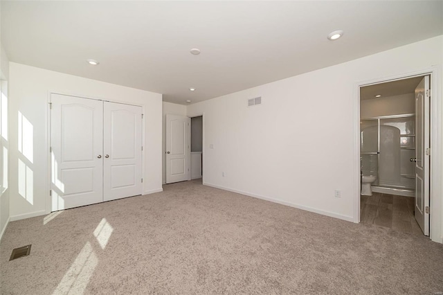 unfurnished bedroom with ensuite bathroom, carpet flooring, and a closet