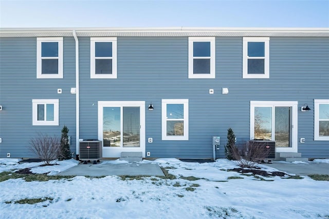 snow covered house featuring cooling unit