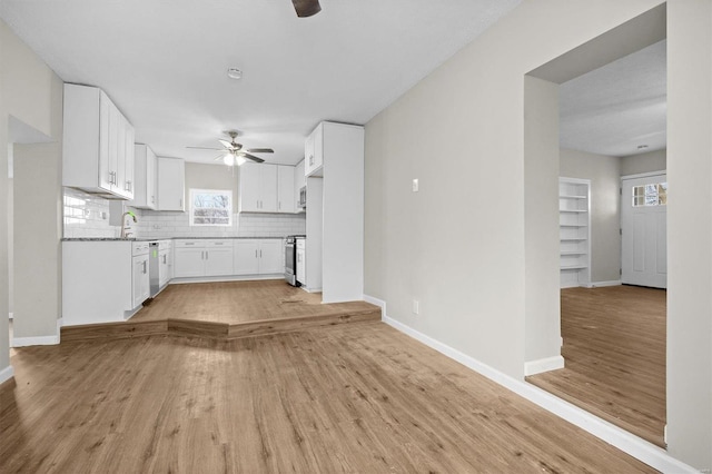 kitchen with light hardwood / wood-style floors, white cabinetry, backsplash, and stainless steel appliances