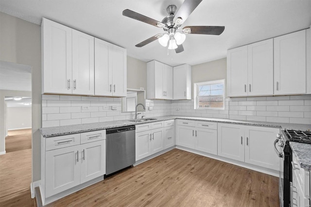 kitchen with backsplash, stainless steel appliances, white cabinetry, and sink