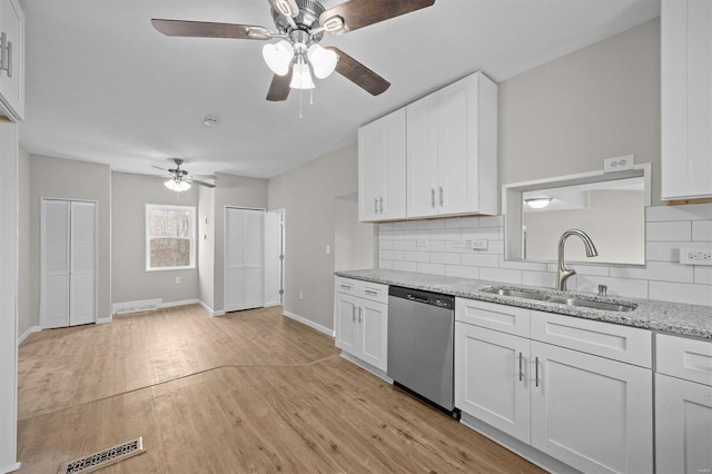 kitchen featuring light stone countertops, tasteful backsplash, stainless steel dishwasher, sink, and white cabinetry