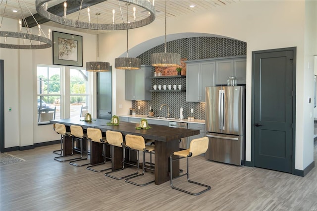 kitchen with pendant lighting, gray cabinets, stainless steel refrigerator, and light wood-type flooring