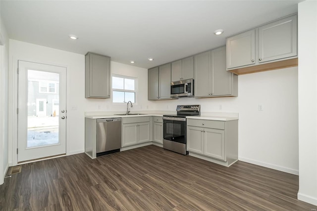 kitchen featuring dark wood-type flooring, stainless steel appliances, gray cabinets, and sink