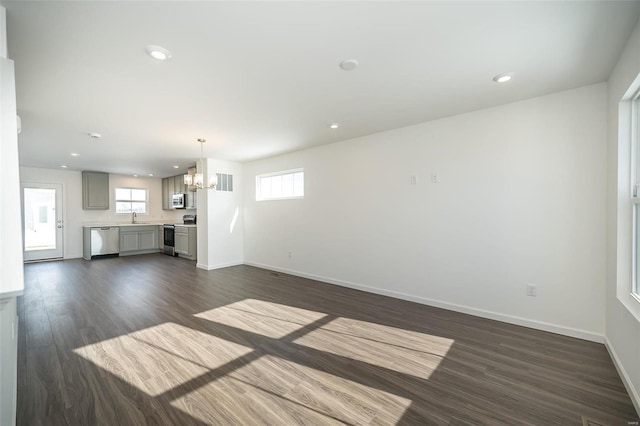 unfurnished living room with a notable chandelier, dark wood-type flooring, and sink