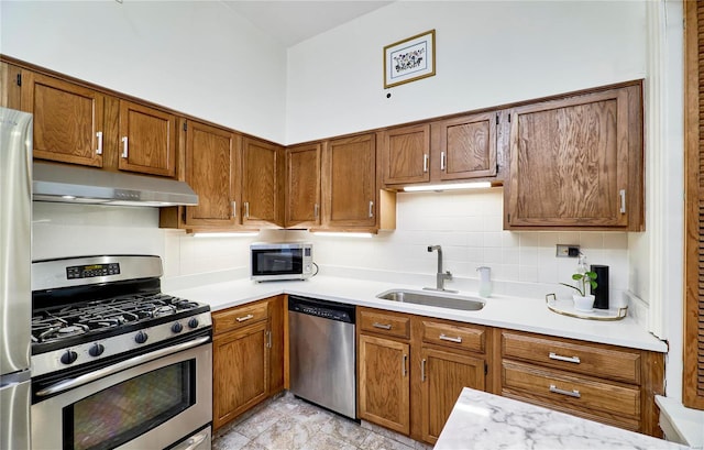 kitchen with a sink, light countertops, under cabinet range hood, and stainless steel appliances